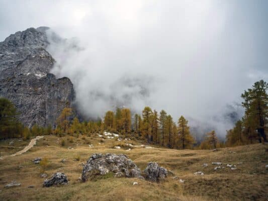 Odľahlá horská krajina s hmlou zahalenými skalnatými vrcholmi a jesenne sfarbenými stromami pri horskej chate Erjavčeva.